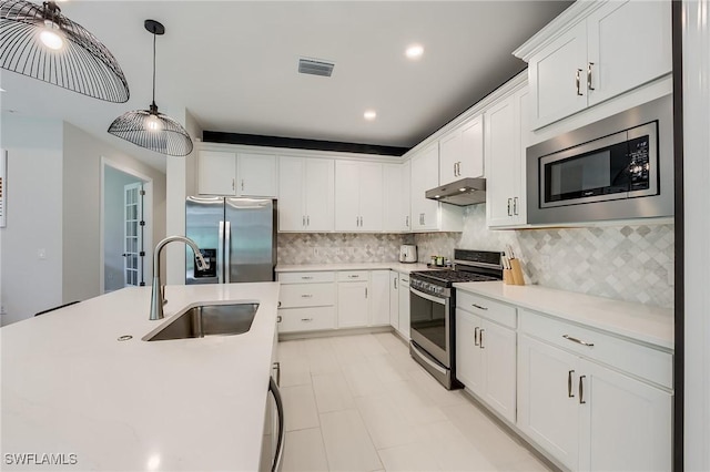 kitchen with decorative light fixtures, white cabinetry, sink, and appliances with stainless steel finishes