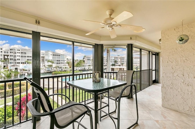 sunroom featuring a water view and ceiling fan