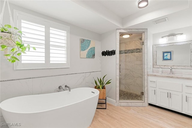 bathroom with plus walk in shower, wood-type flooring, vanity, and a healthy amount of sunlight