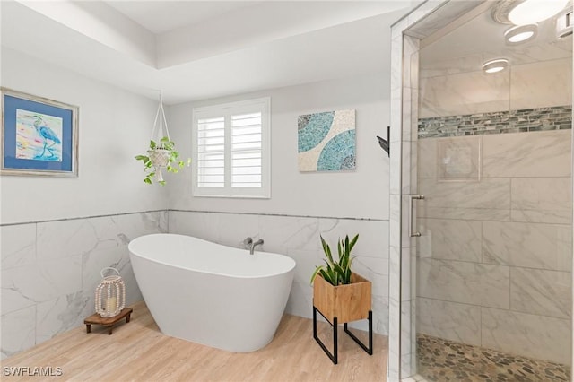 bathroom featuring wood-type flooring, tile walls, and independent shower and bath