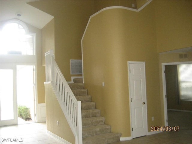 staircase featuring a towering ceiling and tile patterned floors