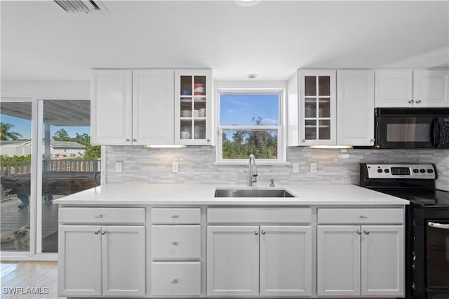 kitchen with white cabinets, electric range oven, tasteful backsplash, and sink