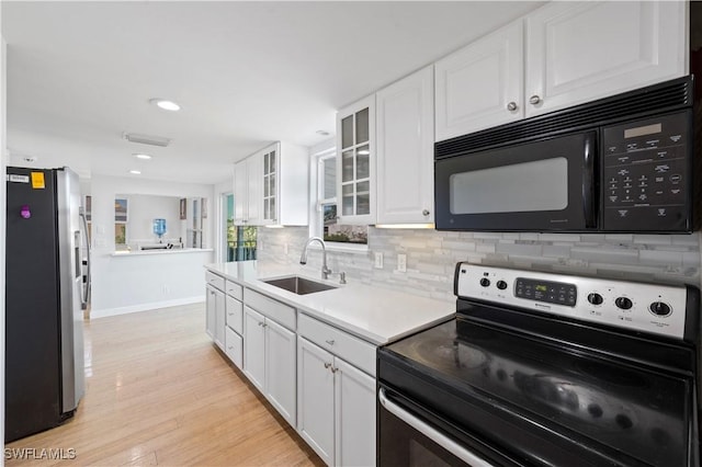 kitchen with sink, light hardwood / wood-style flooring, backsplash, white cabinets, and black appliances