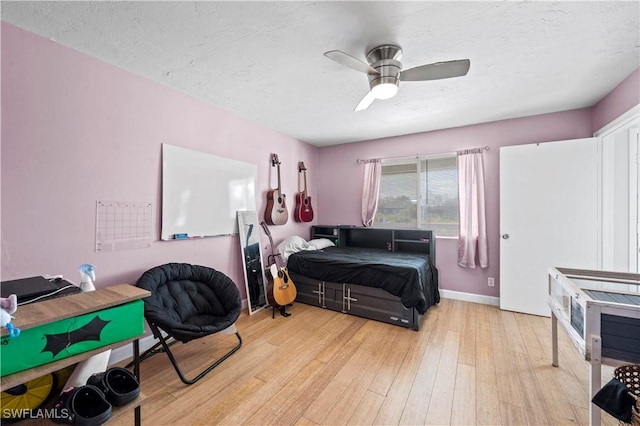 bedroom featuring ceiling fan, light hardwood / wood-style floors, and a textured ceiling