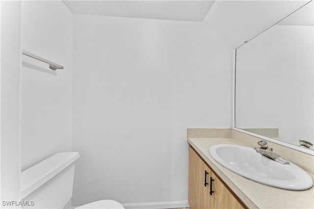 bathroom with vanity, toilet, and vaulted ceiling