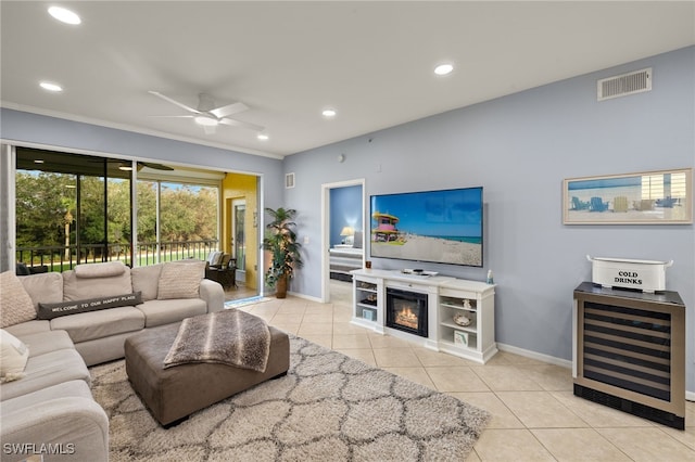 tiled living room featuring a fireplace, ceiling fan, and beverage cooler