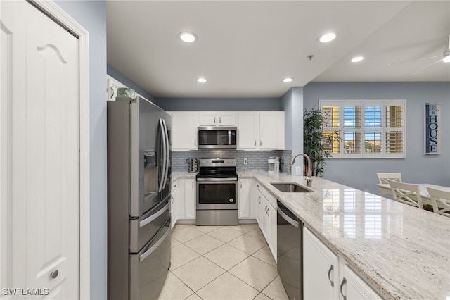 kitchen with white cabinets, appliances with stainless steel finishes, light stone counters, and sink