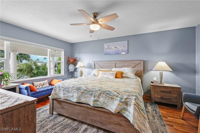 bedroom with ceiling fan, dark wood-type flooring, and a textured ceiling