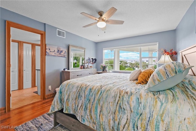 bedroom featuring ceiling fan, light hardwood / wood-style flooring, and a textured ceiling