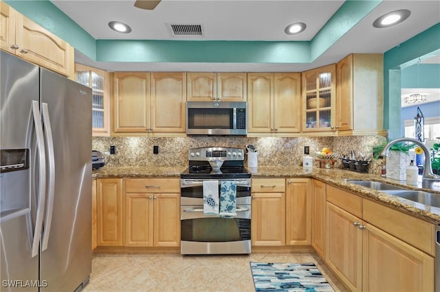 kitchen featuring light brown cabinets, stainless steel appliances, light stone counters, and sink