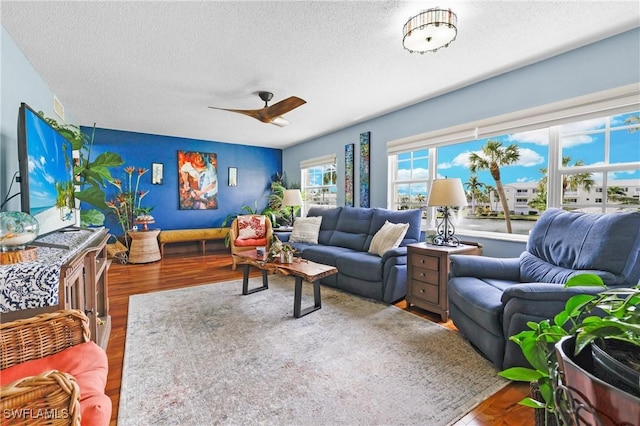 living room with ceiling fan, wood-type flooring, and a textured ceiling