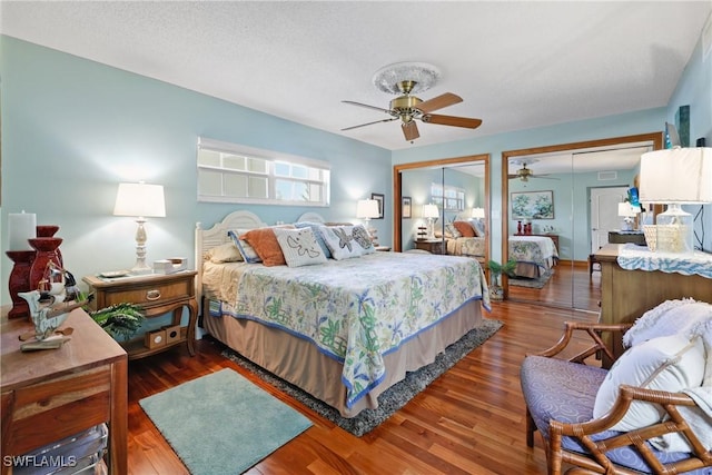 bedroom with two closets, ceiling fan, and dark hardwood / wood-style floors