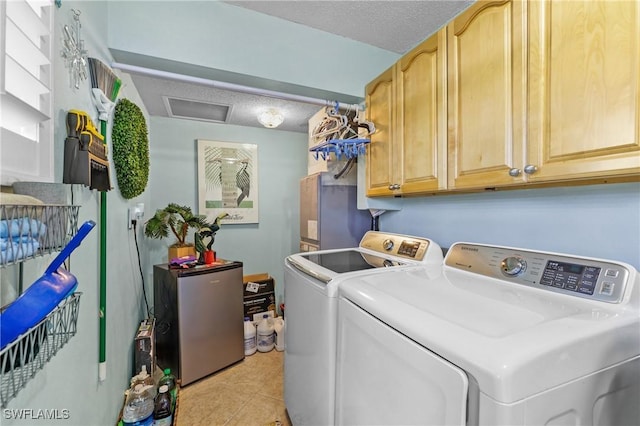 washroom featuring cabinets, light tile patterned floors, a textured ceiling, and washing machine and clothes dryer