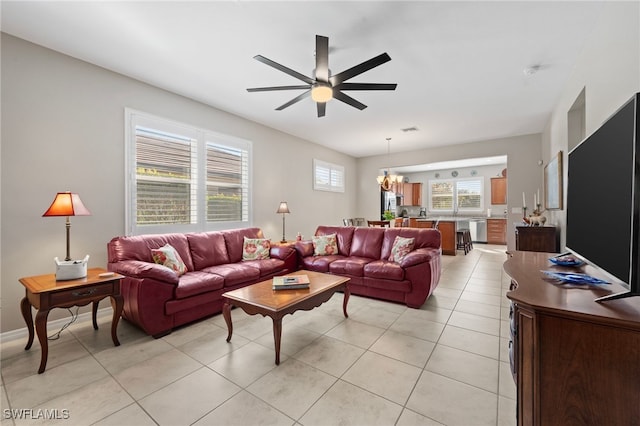 tiled living room featuring ceiling fan with notable chandelier