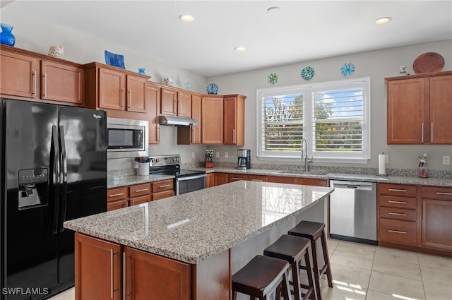 kitchen with light stone countertops, sink, a kitchen island, and appliances with stainless steel finishes