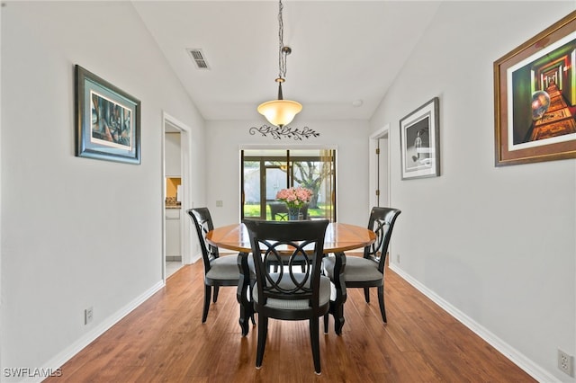 dining area with hardwood / wood-style flooring and vaulted ceiling