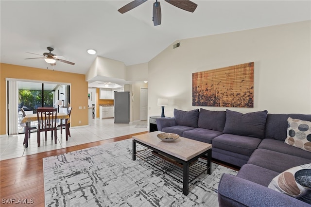 living room featuring ceiling fan, light wood-type flooring, and vaulted ceiling