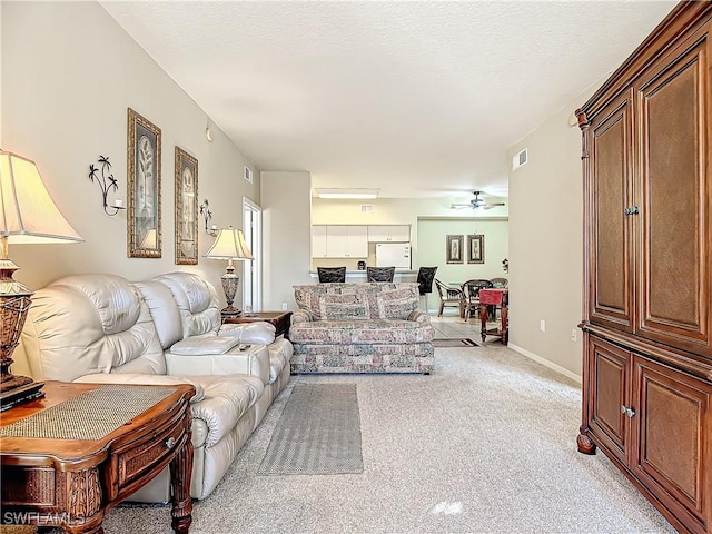 carpeted living room with ceiling fan and a textured ceiling