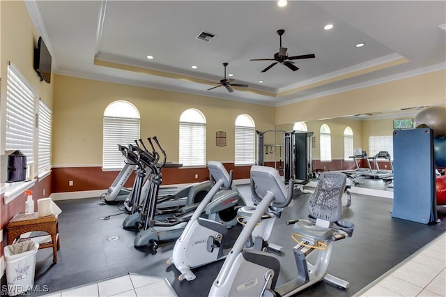 gym featuring ornamental molding, a tray ceiling, and a wealth of natural light