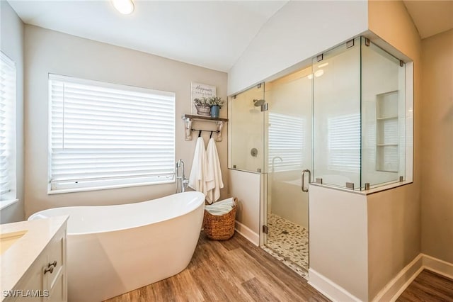 bathroom featuring a healthy amount of sunlight, wood-type flooring, plus walk in shower, and vaulted ceiling