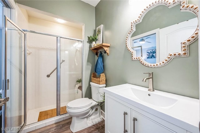 bathroom featuring vanity, a shower with door, ceiling fan, wood-type flooring, and toilet