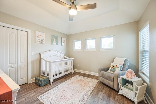 bedroom featuring ceiling fan, a closet, a nursery area, and wood-type flooring