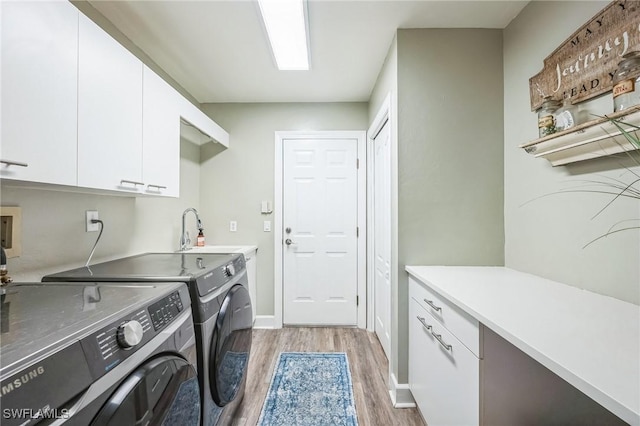 laundry room with cabinets, light wood-type flooring, washer and clothes dryer, and sink