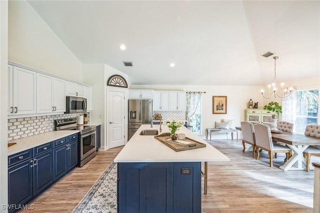 kitchen with blue cabinetry, decorative backsplash, an island with sink, and stainless steel appliances