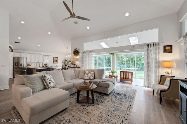 living room with hardwood / wood-style flooring, high vaulted ceiling, ceiling fan, and sink