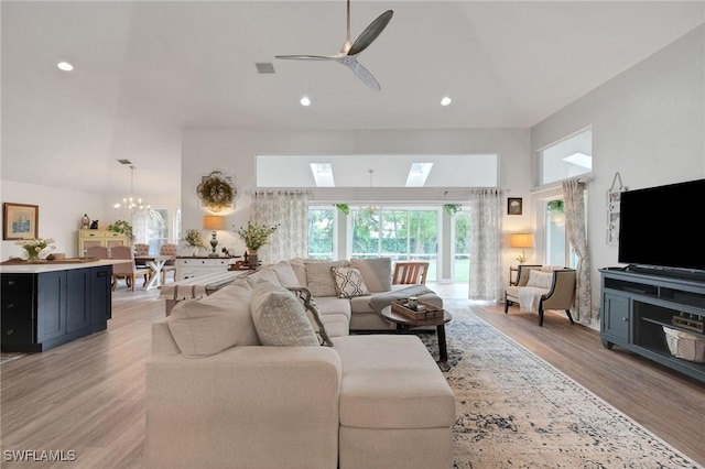 living room featuring ceiling fan with notable chandelier and light hardwood / wood-style flooring