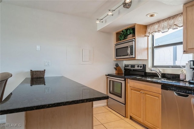 kitchen featuring dark stone counters, sink, light tile patterned flooring, kitchen peninsula, and stainless steel appliances