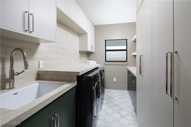 laundry area with light floors, cabinet space, a sink, washer and dryer, and baseboards