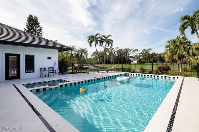 view of pool featuring a patio area, a pool with connected hot tub, and fence