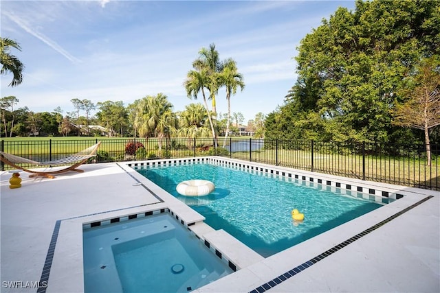 view of swimming pool with a fenced backyard and a pool with connected hot tub