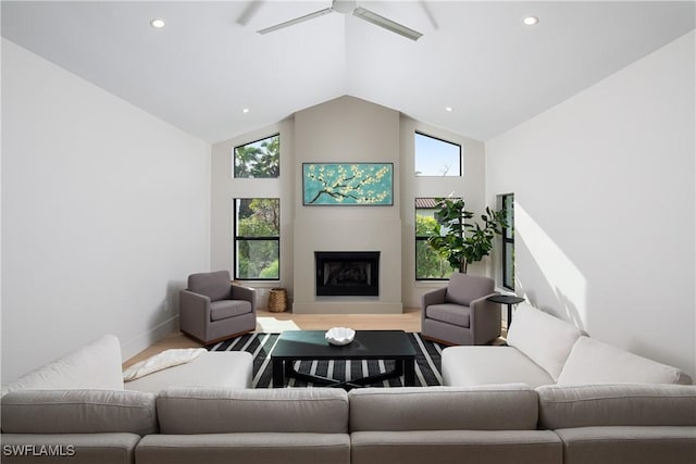 living area featuring high vaulted ceiling, a fireplace, wood finished floors, and a healthy amount of sunlight