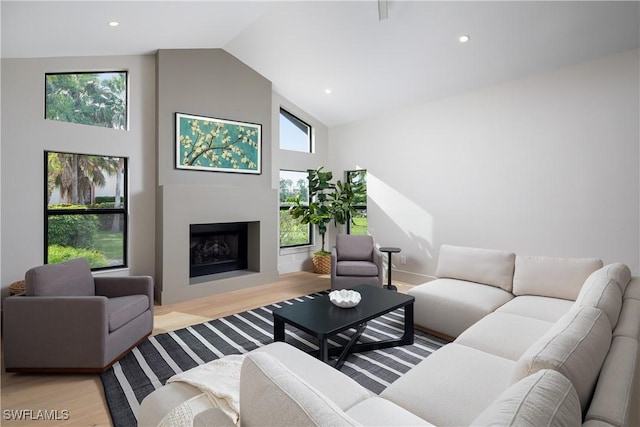 living area with high vaulted ceiling, recessed lighting, a fireplace, and wood finished floors