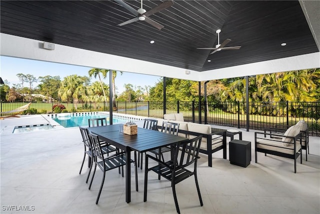 view of patio / terrace with a fenced backyard, a pool with connected hot tub, a ceiling fan, and outdoor dining space