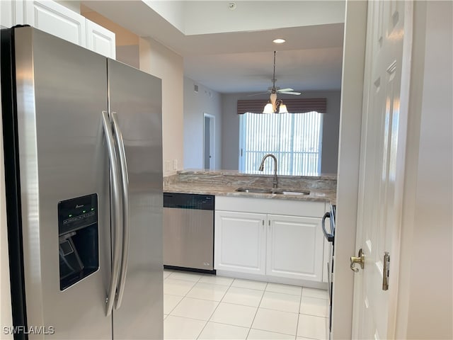 kitchen featuring appliances with stainless steel finishes, light stone counters, sink, light tile patterned floors, and white cabinets