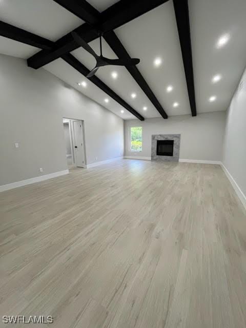 unfurnished living room with vaulted ceiling with beams, light wood-type flooring, and a premium fireplace