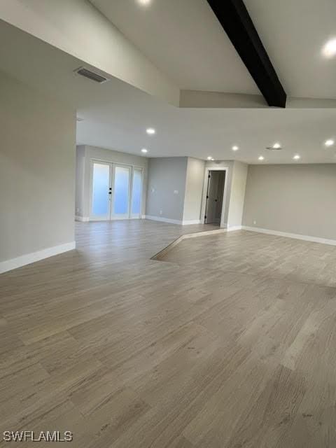 spare room with beam ceiling and light wood-type flooring