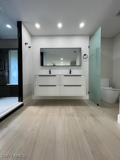 bathroom with hardwood / wood-style flooring, vanity, toilet, and a shower