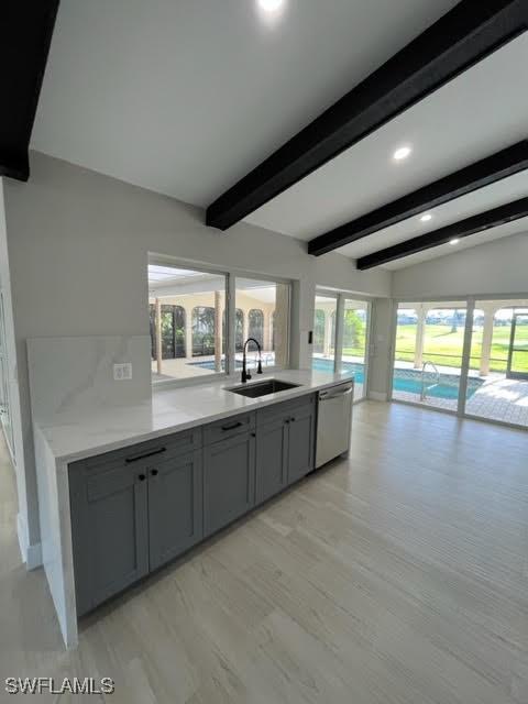 kitchen featuring sink, light hardwood / wood-style flooring, stainless steel dishwasher, vaulted ceiling with beams, and gray cabinets