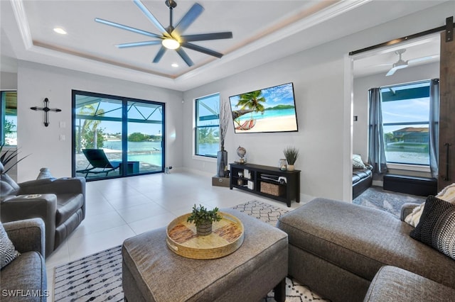 tiled living room with ceiling fan, a barn door, and a tray ceiling