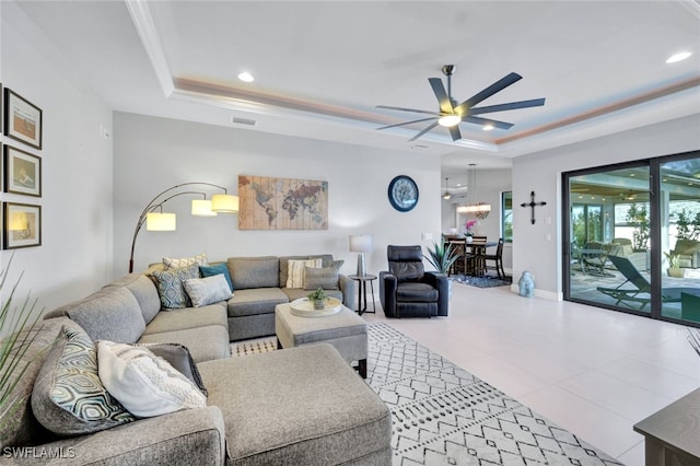 living room with a tray ceiling, ceiling fan, and crown molding