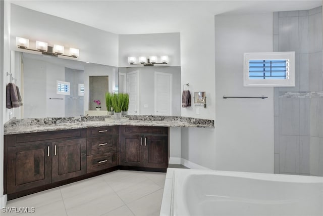 bathroom with tile patterned floors, a bathtub, and vanity