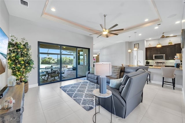 tiled living room with a tray ceiling, ceiling fan, and sink