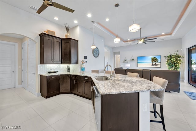 kitchen featuring sink, a raised ceiling, decorative light fixtures, a kitchen bar, and decorative backsplash