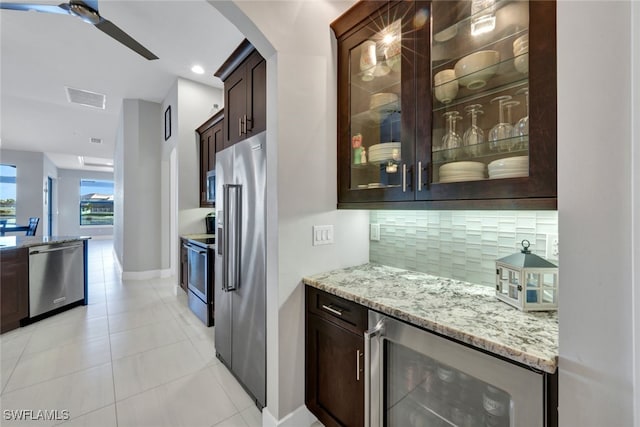 kitchen with beverage cooler, light stone countertops, appliances with stainless steel finishes, and tasteful backsplash