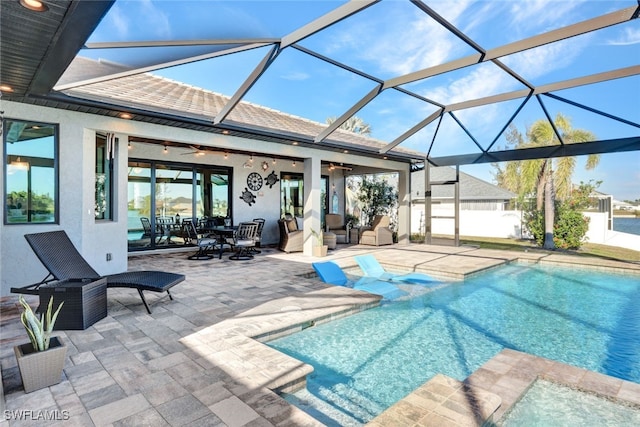 view of swimming pool featuring a patio, glass enclosure, and ceiling fan