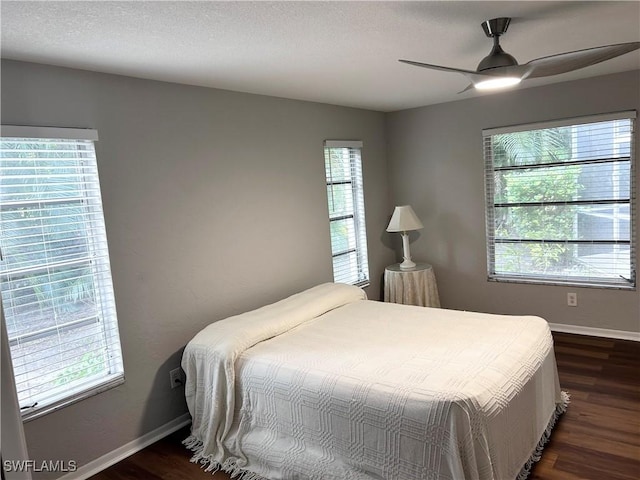 bedroom with multiple windows, dark hardwood / wood-style flooring, and ceiling fan